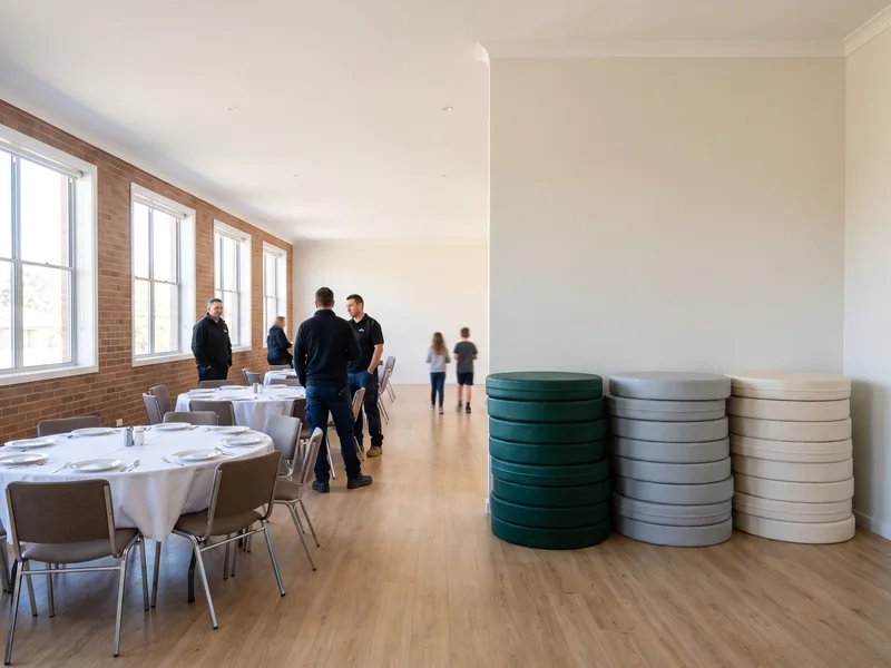 Fellowship hall set with round tables, soft play modules stacked by the wall