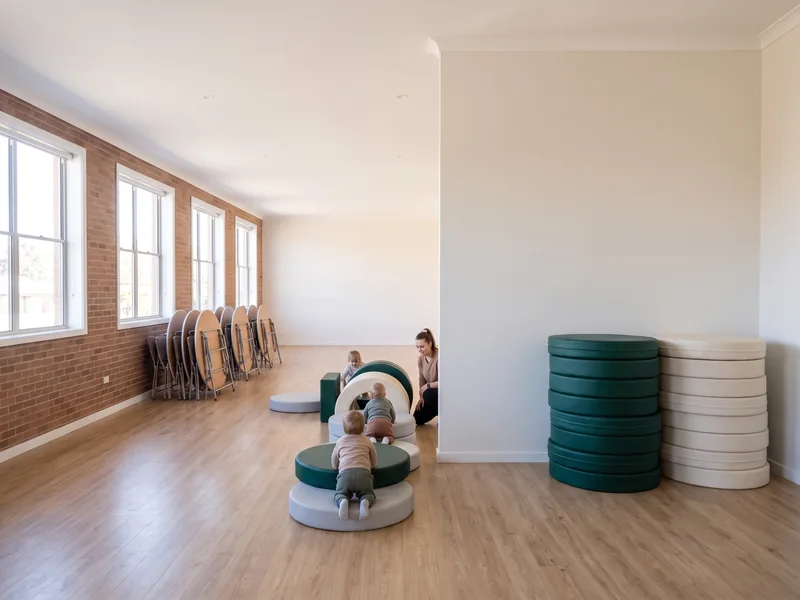 The same fellowship hall with tables folded away and soft play modules laid out as a crawl route