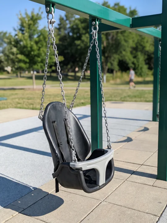 An inclusive high-back swing seat with a harness hanging still in its own bay
