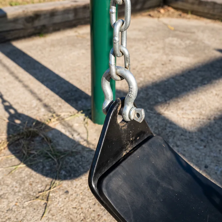 A closed shackle joining a galvanized swing chain to a seat bracket