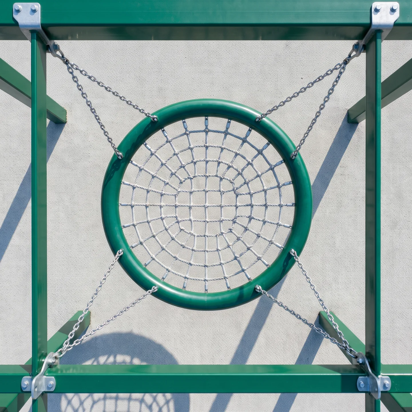 A nest swing seen from directly above: the padded steel ring, the rope net and the hanging chains running out to the beam