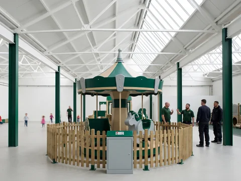 Small evergreen and sand carousel for young children inside an FEC entrance