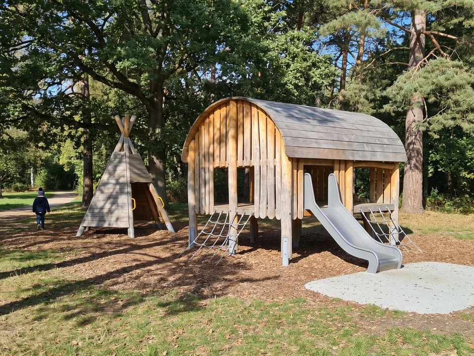 A timber play hut and a timber teepee in a quiet corner