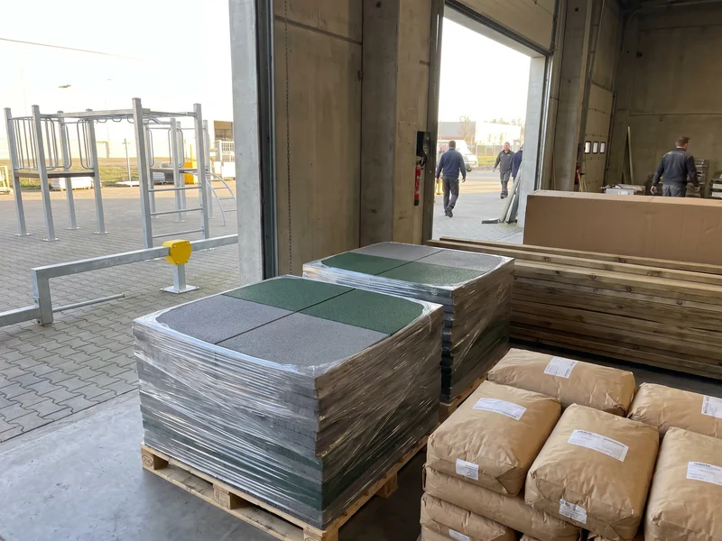 Pallets of grey and evergreen rubber safety tiles stacked and strapped for shipping