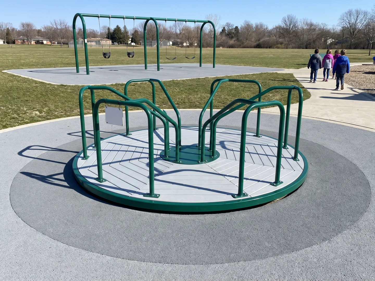 A classic merry-go-round with a continuous ring of surfacing around it and a swing frame outside the ring