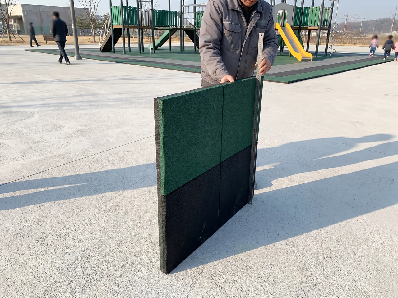 A two-layer rubber tile cross-section beside a steel rule