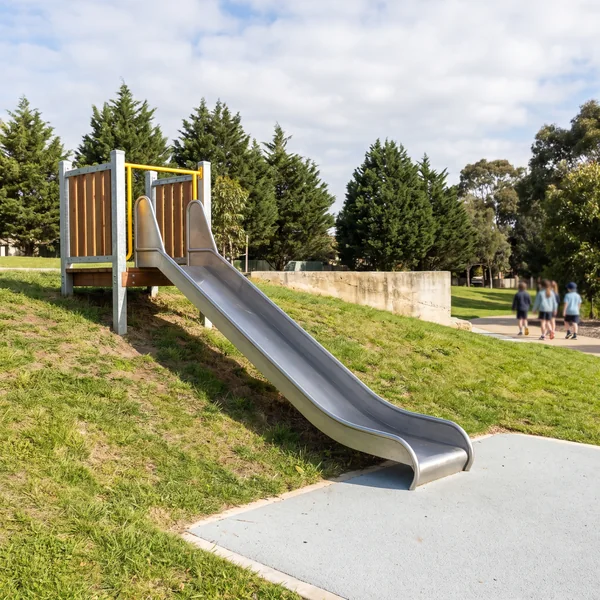 A stainless steel embankment slide laid down a grassy park slope
