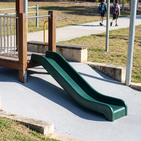 A short evergreen straight slide running from a low deck of a commercial play structure
