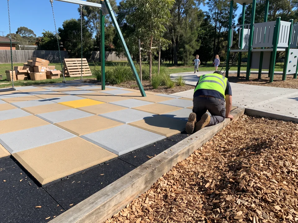 Wood chip play area meeting a rubber tile area along a clear edging