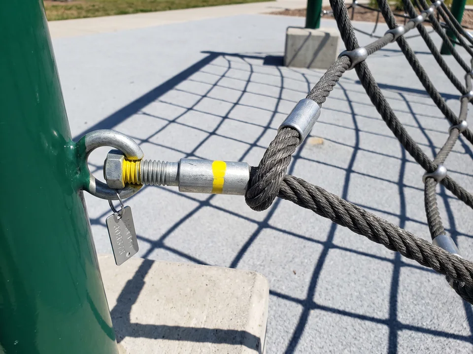 A tensioning bolt with a colored mark on its thread and a numbered tag at the anchor point