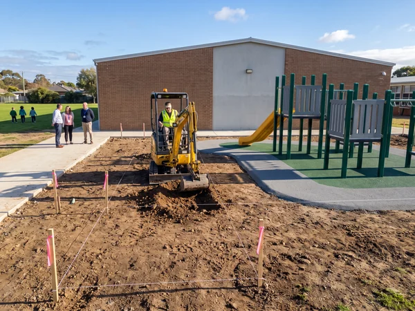 Contractor digging new footing holes on a cleared school playground
