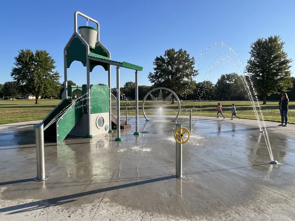 A multi-feature water play structure with an evergreen fiberglass frame, a tipping bucket and a platform